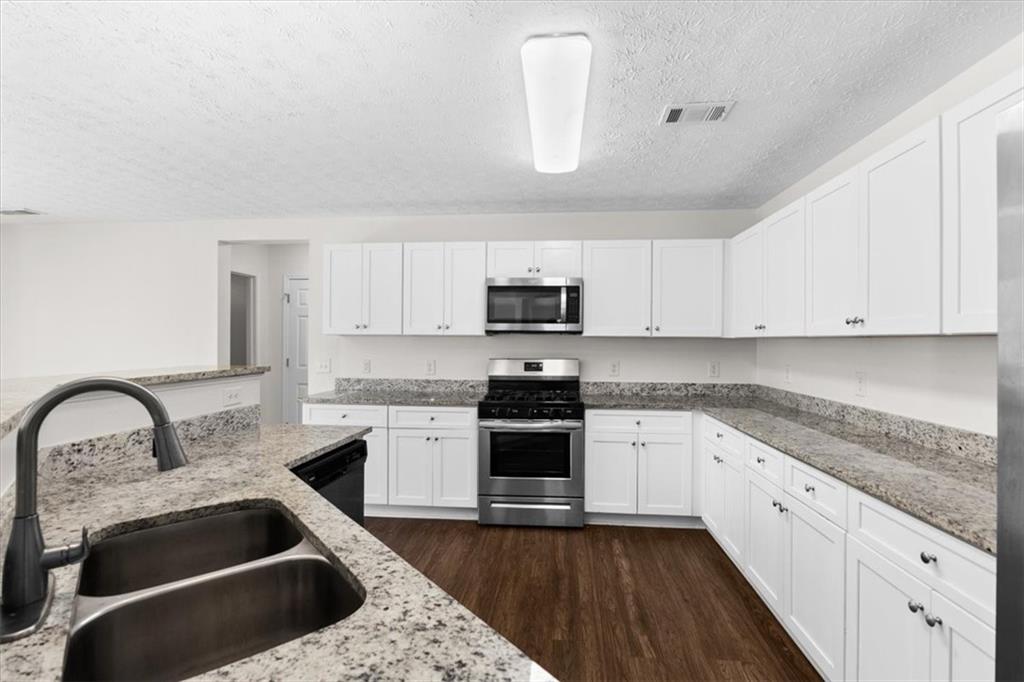 2068 White Top Road Southeast Lawrenceville, GA 30045 - Photo 16 of 41 a kitchen with granite countertop a sink stainless steel appliances and white cabinets
