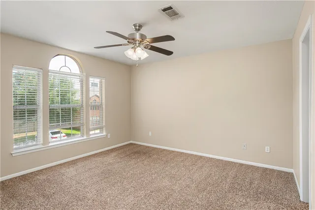 an empty room with windows and fan