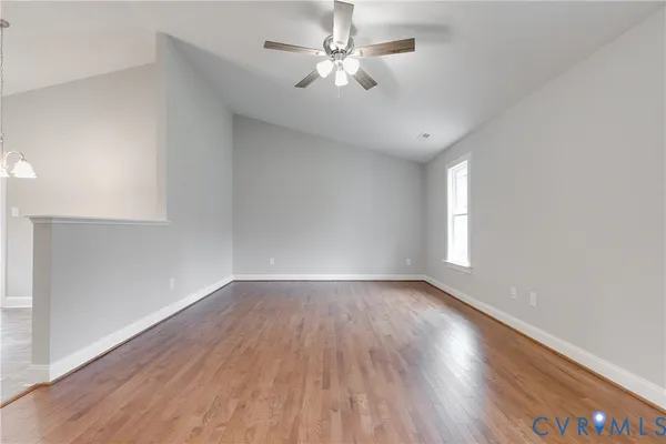 an empty room with wooden floor and a ceiling fan
