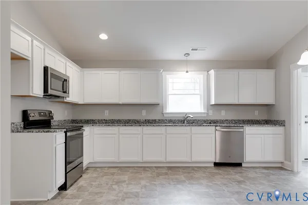 a kitchen with granite countertop white cabinets and stainless steel appliances