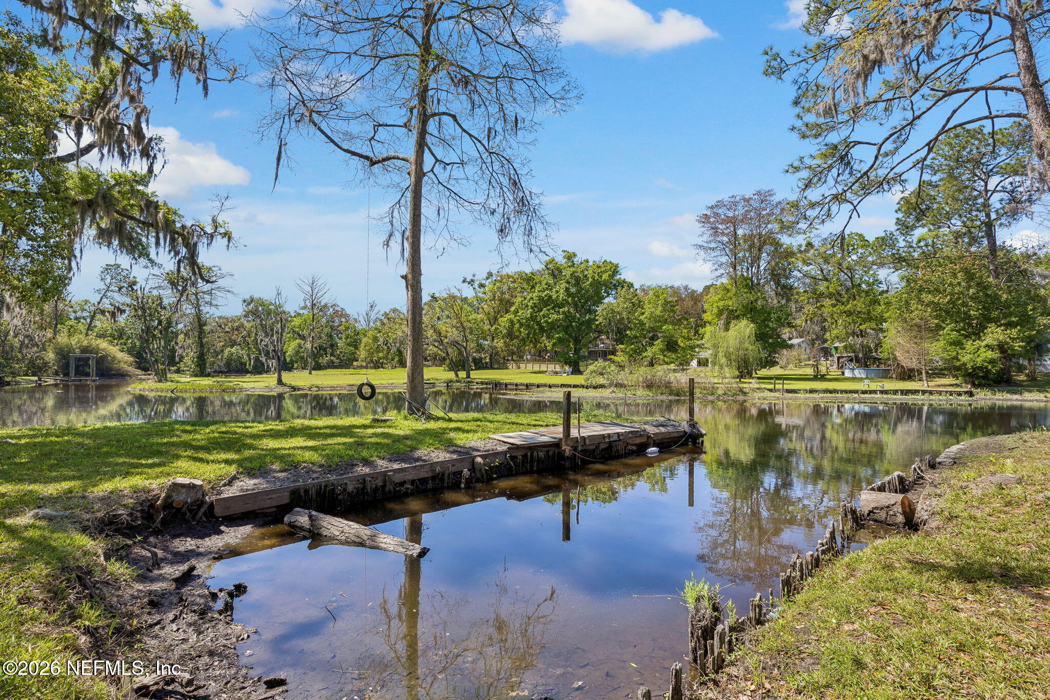 a view of a lake with a yard and large trees