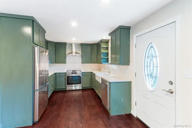 a kitchen with stainless steel appliances a kitchen island wooden floors and white cabinets