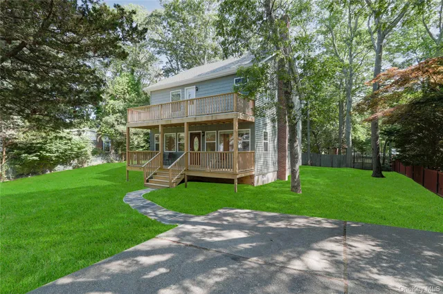 a view of a small house with a big yard and large trees