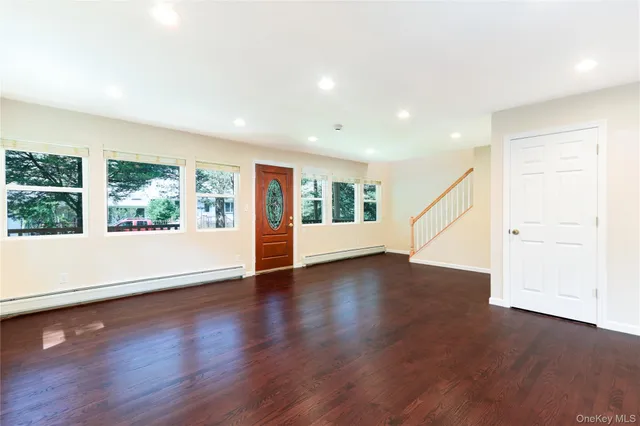 a view of an empty room with wooden floor and windows