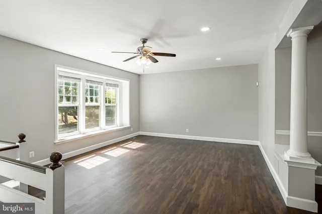 a view of an empty room with a window and wooden floor