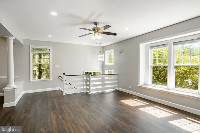 a view of an empty room with a window and wooden floor