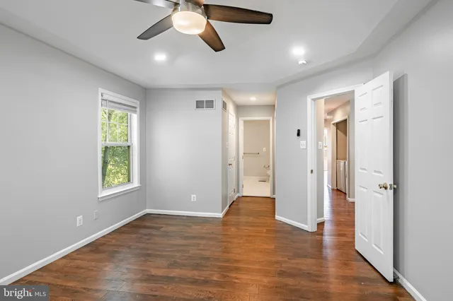 a view of an empty room with window and wooden floor