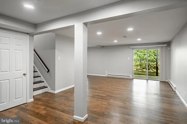 a view of an empty room with wooden floor and stairs