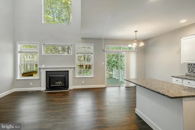 an empty room with wooden floor fireplace and windows