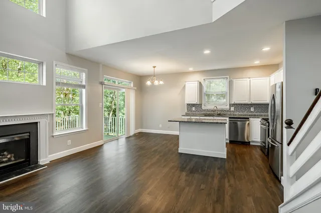 a large kitchen with granite countertop a stove top oven a sink dishwasher a refrigerator white cabinets and wooden floor