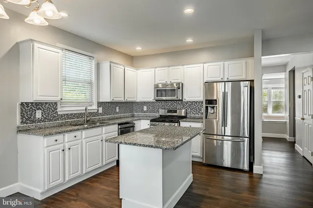 a kitchen with stainless steel appliances granite countertop a refrigerator a sink dishwasher a stove and a refrigerator