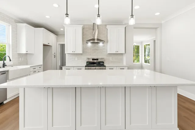 a kitchen with stainless steel appliances granite countertop a sink a stove and a wooden floors