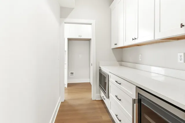 a view of a kitchen with white cabinets and wooden floor