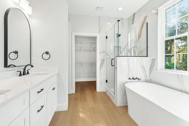a spacious bathroom with a double vanity sink a mirror and a bathtub