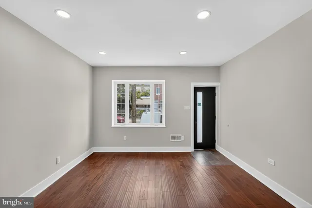 an empty room with wooden floor and windows