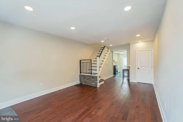an empty room with wooden floor and stairs