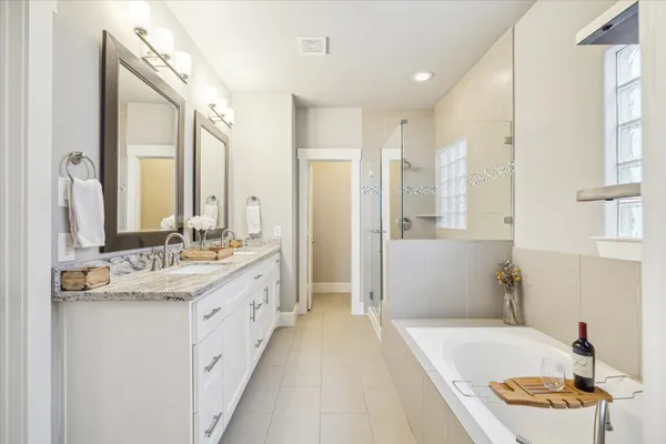 a bathroom with a granite countertop sink a mirror a bathtub and shower