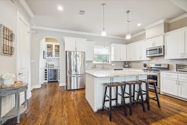 a kitchen with stainless steel appliances granite countertop a refrigerator a stove top oven a sink dishwasher and white cabinets with wooden floor