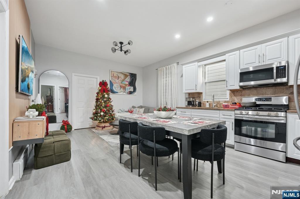 717 16th Street Union City, NJ 07087 - Photo 5 of 27 a kitchen with stainless steel appliances granite countertop a stove top oven a sink a dining table and chairs with wooden floor