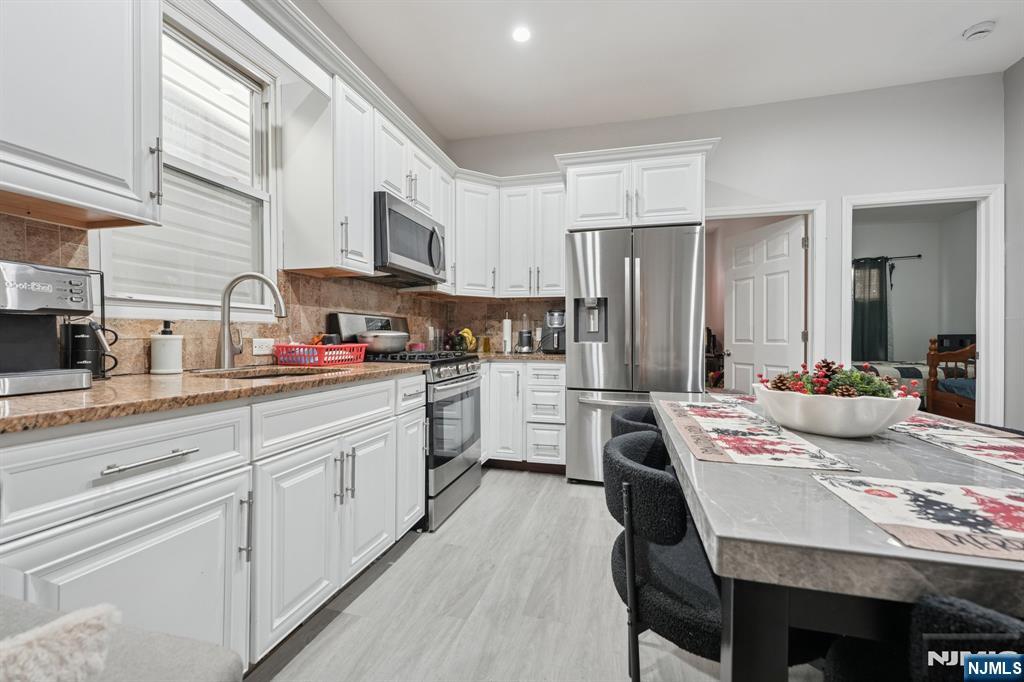 717 16th Street Union City, NJ 07087 - Photo 7 of 27 a kitchen with stainless steel appliances granite countertop a stove a sink dishwasher a refrigerator with white cabinets and wooden floor