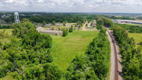 a view of a lake with lawn chairs and large trees