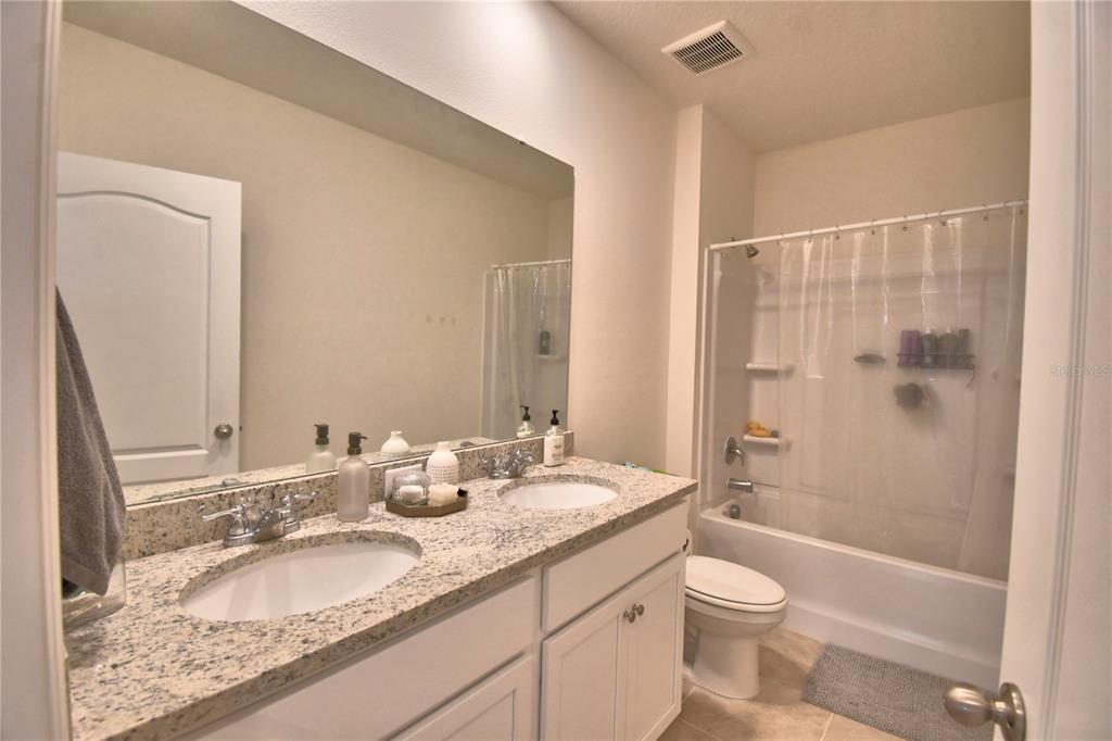 2839 Moulin Road Davenport, FL 33837 - Photo 49 of 75 a bathroom with a granite countertop sink toilet mirror and shower