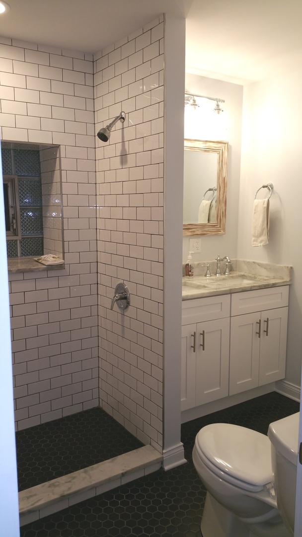 1309 West Fillmore Street, Unit 1 Chicago, IL 60607 - Photo 4 of 9 a bathroom with a granite countertop toilet a sink a mirror and shower