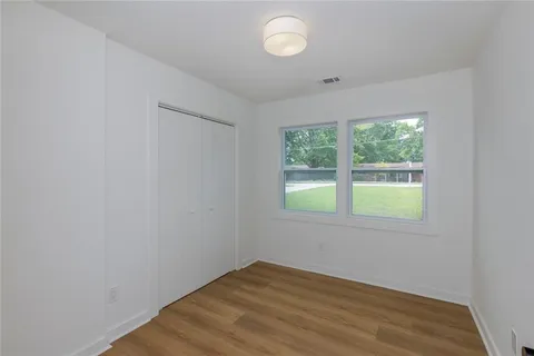 an empty room with wooden floor and windows
