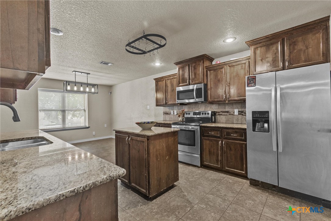 6405 Deorsam Loop Killeen, TX 76542 - Photo 15 of 36 a kitchen with stainless steel appliances granite countertop a stove refrigerator sink and microwave