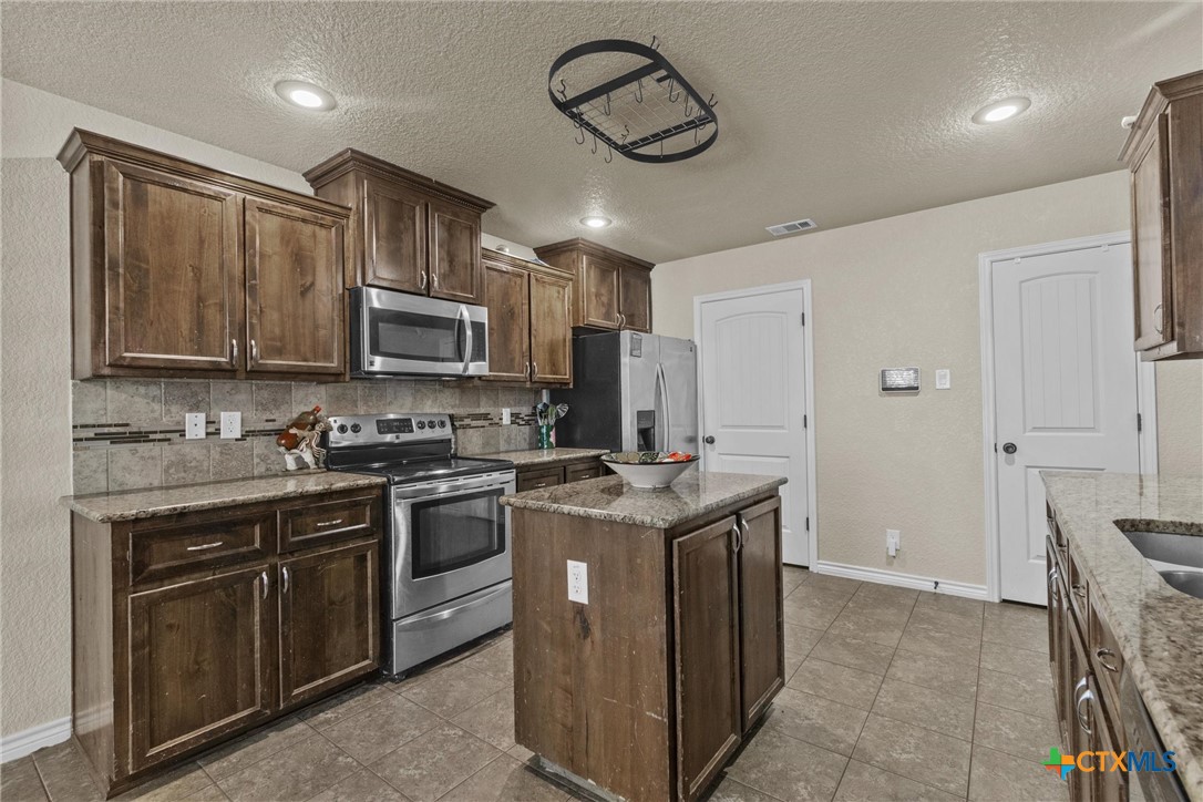 6405 Deorsam Loop Killeen, TX 76542 - Photo 16 of 36 a kitchen with stainless steel appliances granite countertop a stove top oven a sink dishwasher and a refrigerator with wooden cabinets