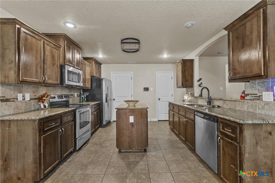 6405 Deorsam Loop Killeen, TX 76542 - Photo 18 of 36 a kitchen with stainless steel appliances granite countertop a sink counter space cabinets and a stove