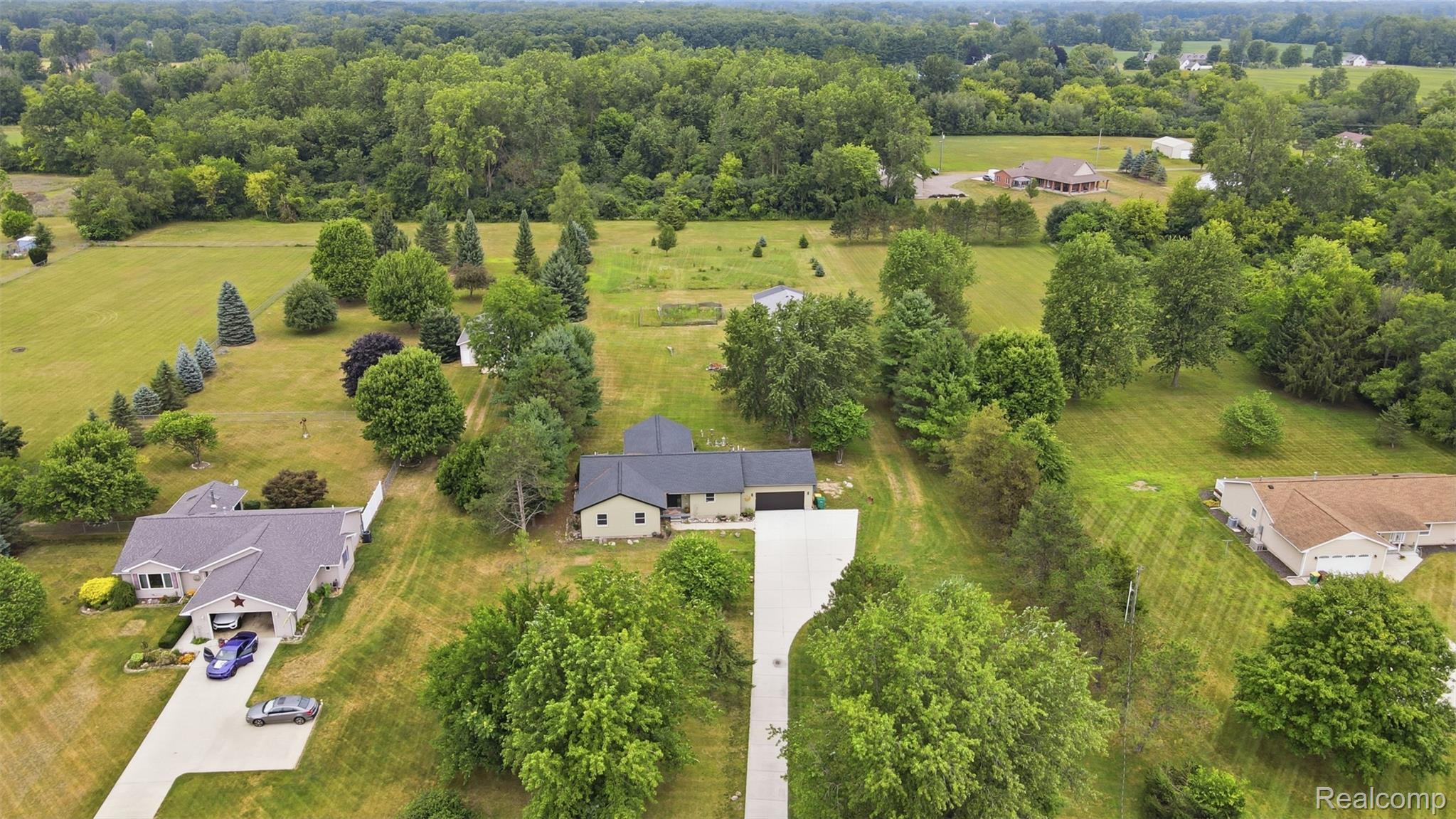 45738 Bemis Road Belleville, MI 48111 - Photo 3 of 52 Sprawling property featuring a single-story residence with an attached garage, extensive green space, mature trees, and a concrete driveway