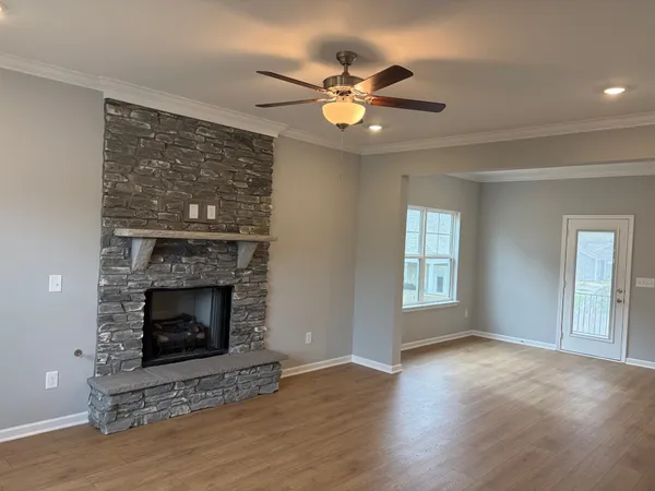 a view of an empty room with wooden floor fireplace and a window