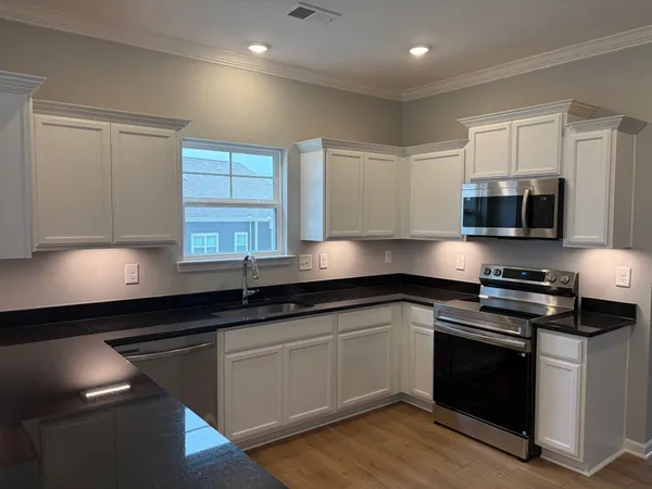 a kitchen with stainless steel appliances a sink dishwasher a stove top oven a refrigerator with wooden floors and cabinets