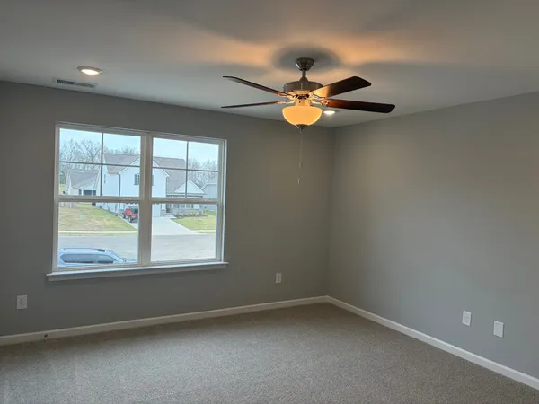 an empty room with a window and a fan