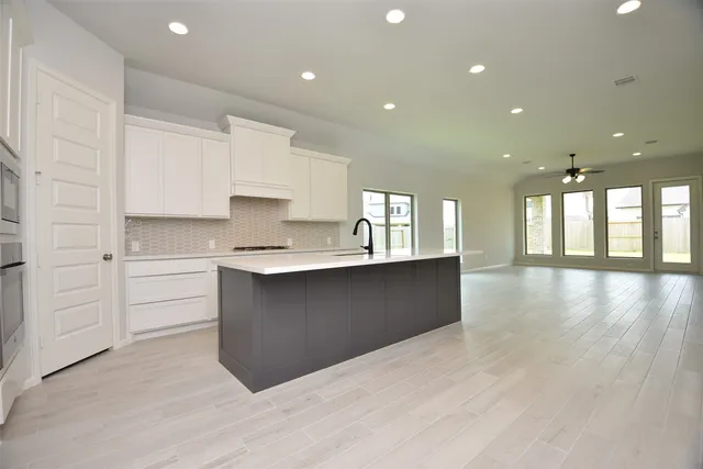 a large kitchen with stainless steel appliances granite countertop a large counter top a sink and a large window