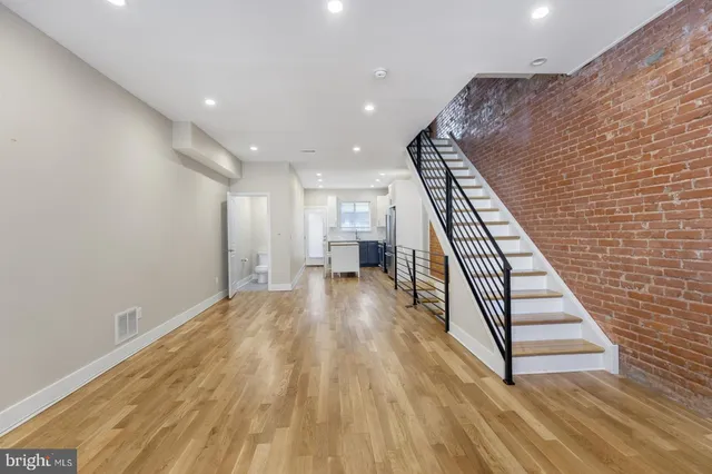 a view of an empty room with wooden floor and stairs