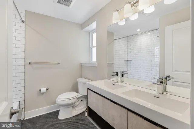 a bathroom with a double vanity sink toilet and a mirror
