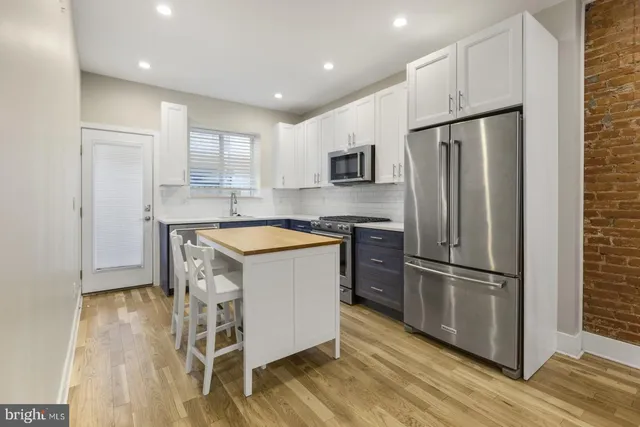 a kitchen with kitchen island a counter top space stainless steel appliances and cabinets