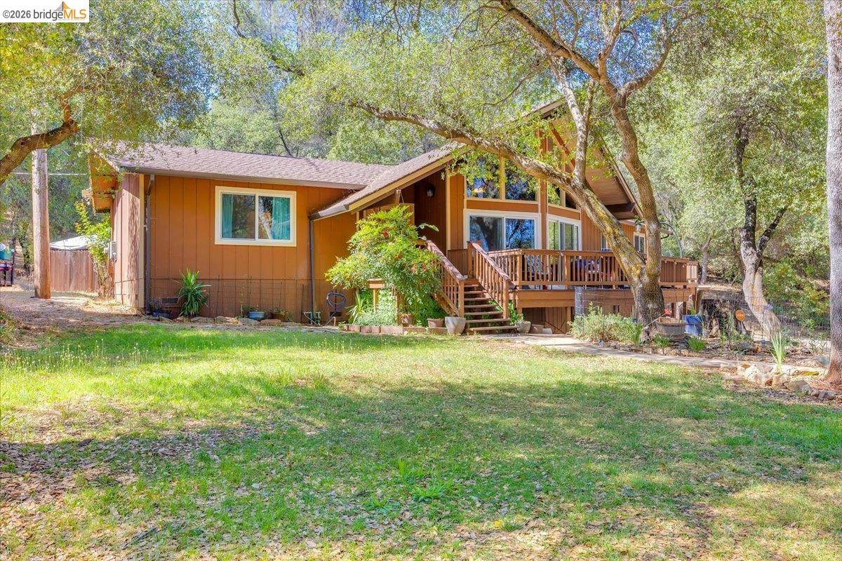 8733 Fraguero Road Sonora, CA 95370 - Photo 10 of 73 Exterior featuring a large wooden deck, expansive windows, a brown siding facade, and a shingled roof