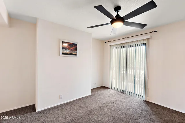 an empty room with ceiling fan and window