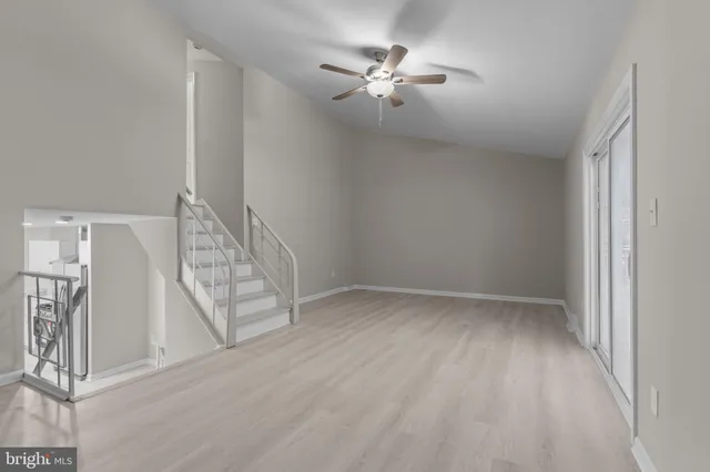 an empty room with wooden floor chandelier fan and windows