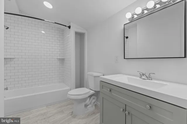 a bathroom with a sink a toilet a mirror a bathtub and shower