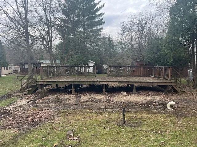 a backyard of a house with large trees and wooden fence