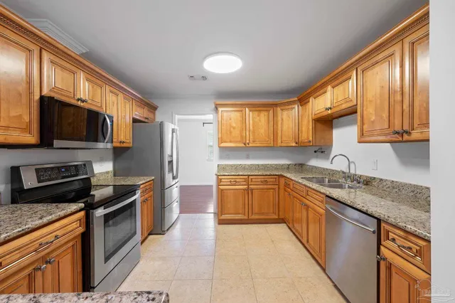 a kitchen with stainless steel appliances granite countertop a stove top oven a sink dishwasher a refrigerator and a microwave oven with cabinets