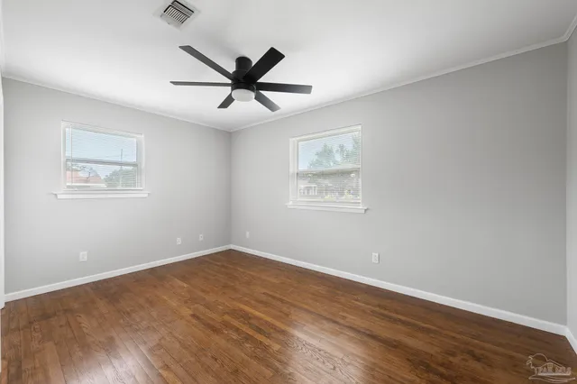 a view of a big room with wooden floor and windows