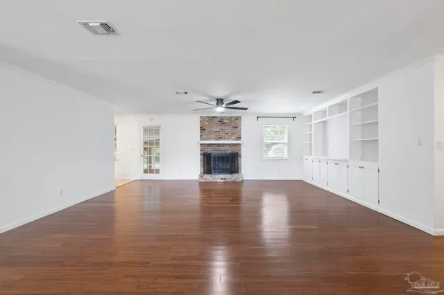a view of an empty room with window and wooden floor