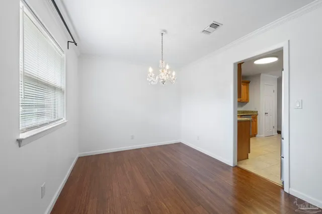 a view of a room with wooden floor chandelier and windows
