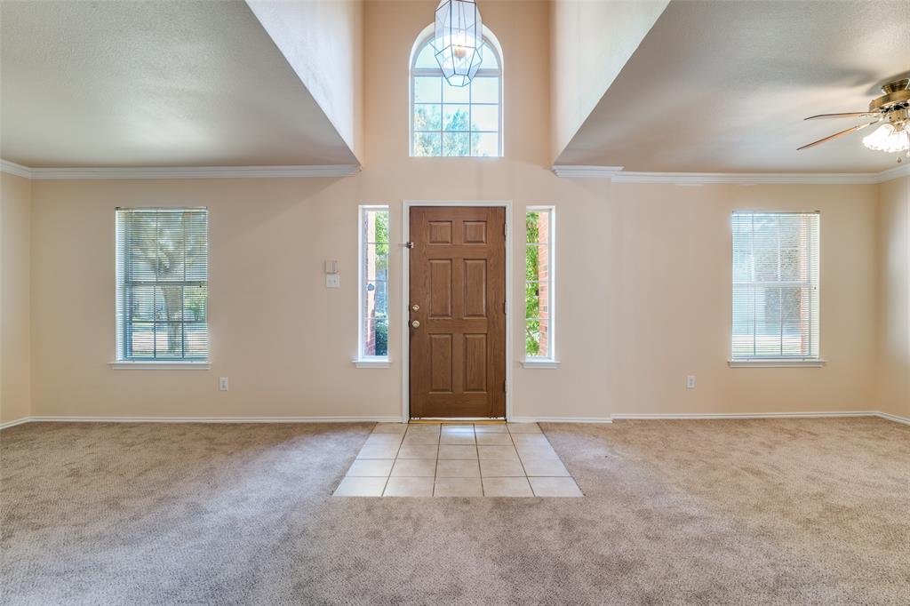 1202 Morrow Lane Allen, TX 75002 - Photo 3 of 35 Entryway featuring ornamental molding, light colored carpet, healthy amount of natural light, a ceiling fan, and a high ceiling