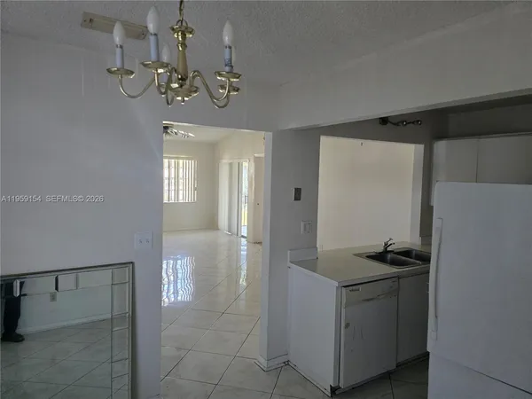 a hallway with white cabinets and chandelier